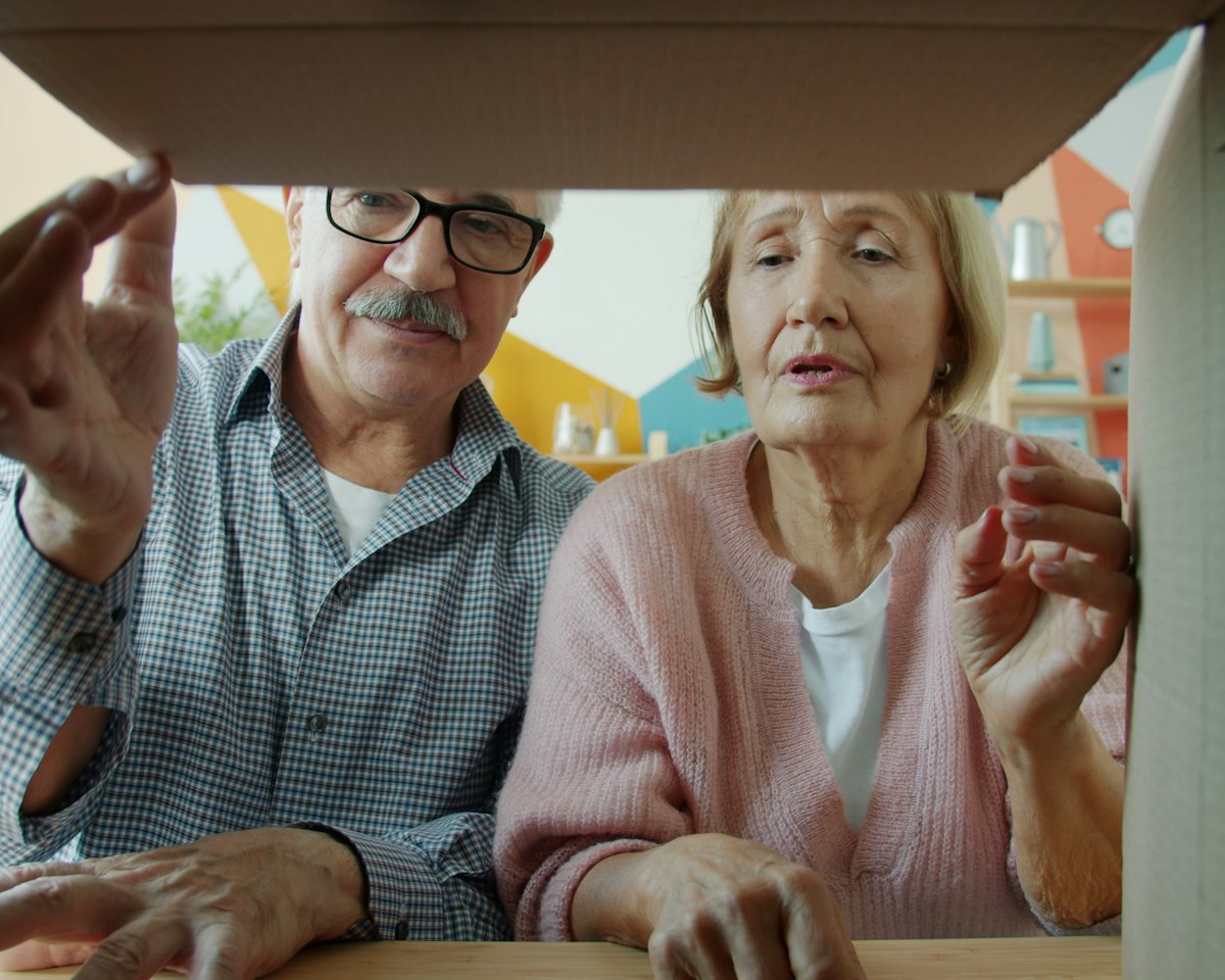 A senior couple opens a cardboard delivery box together at home