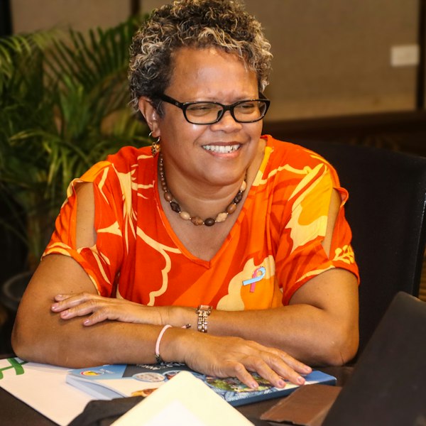Margaret Okafor, a smiling reader in an orange blouse and glasses